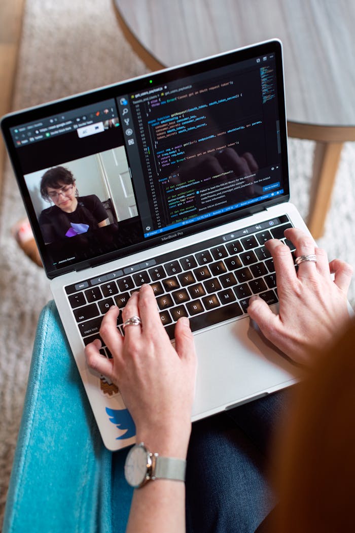 gallery-04 Person coding on a laptop during a video conference, showcasing remote work.